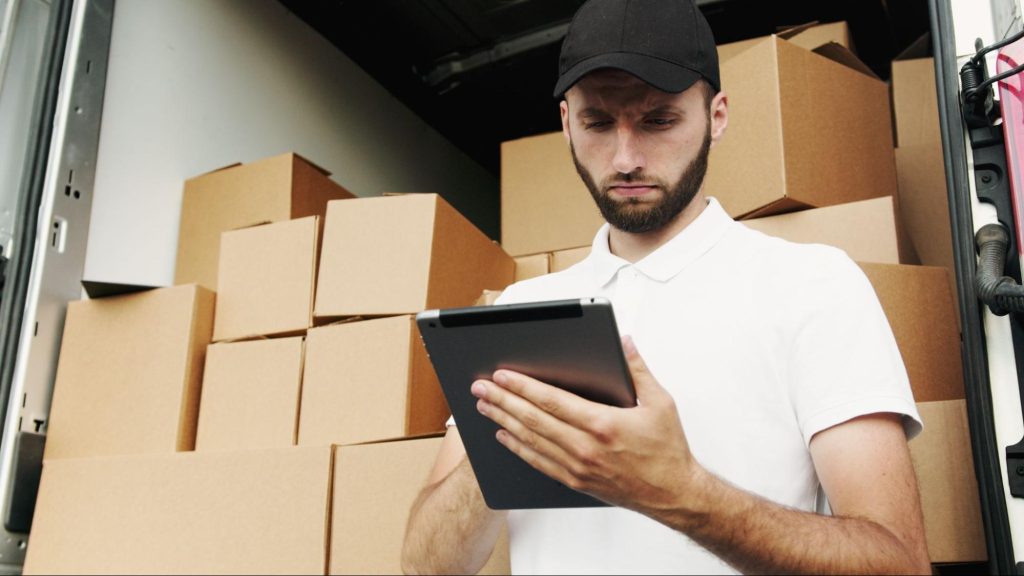 Man standing in front of moving boxes with clipboard