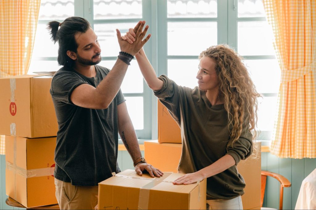 Couple high-fiving with moving boxes